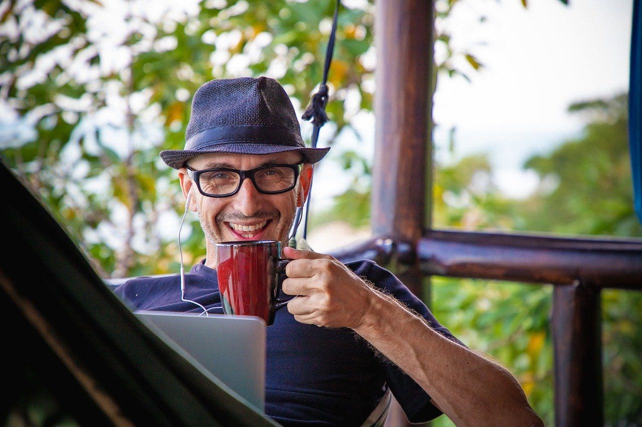 man sitting in a hammock working remotely