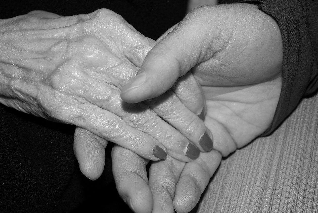 elderly person and caregiver holding hands