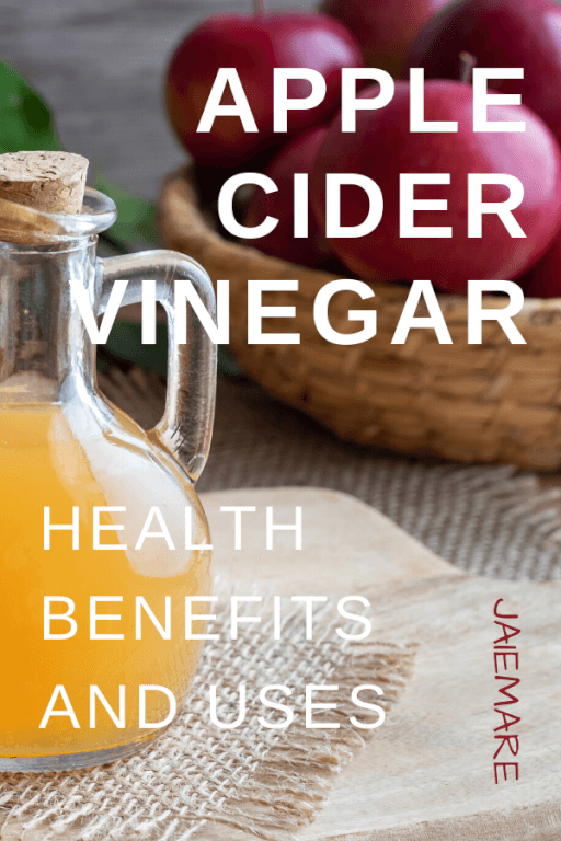 Apple cider vinegar liquid and apples sitting on a table. 