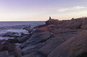 Woman sitting on rocks overlooking Lake Superior.